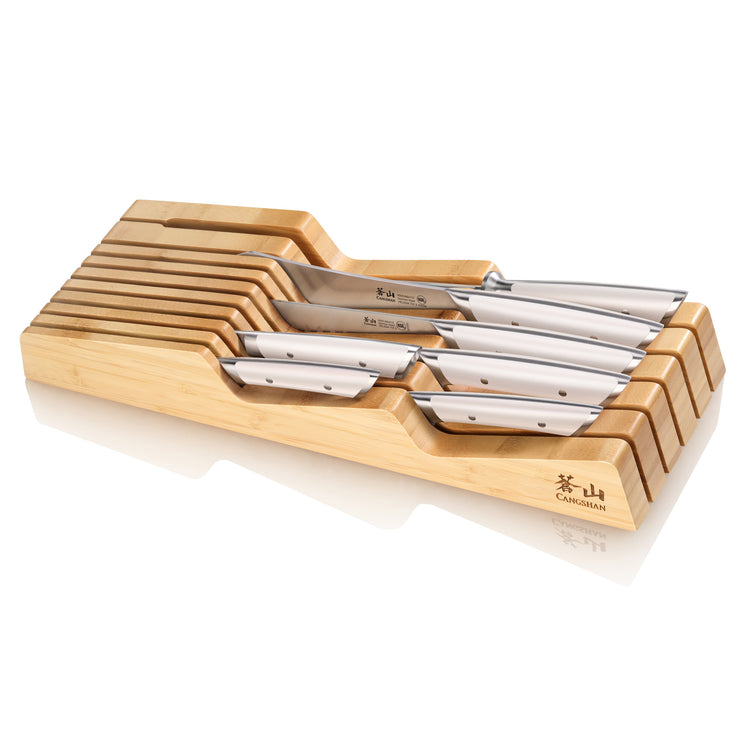 Eight stainless steel knives with silver handles arranged in a bamboo in-drawer knife organizer.