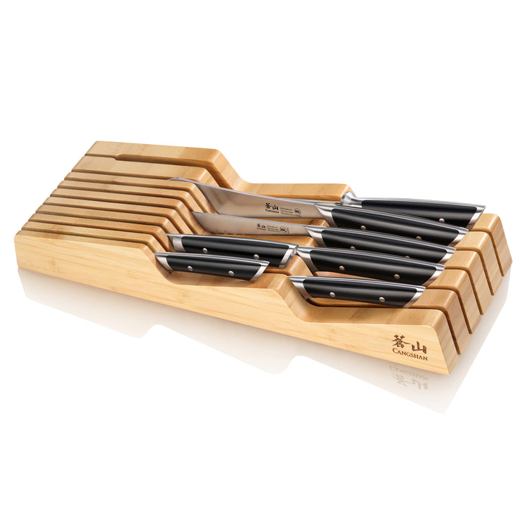 Eight-piece knife set with black handles neatly arranged in a bamboo in-drawer organizer.