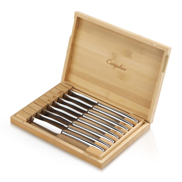 Eight stainless steel steak knives with curved handles arranged in a bamboo storage box with an open lid.