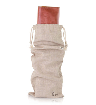 
                    
                      Beige drawstring fabric bag partially covering a rolled-up brown leather knife case.
                    
                  