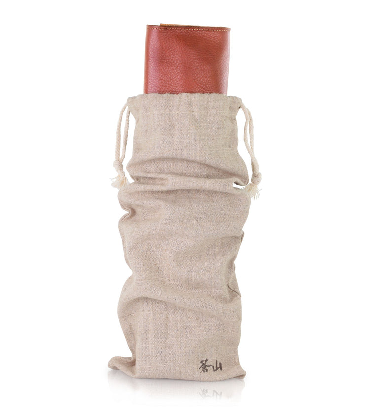 Beige drawstring fabric bag partially covering a rolled-up brown leather knife case.