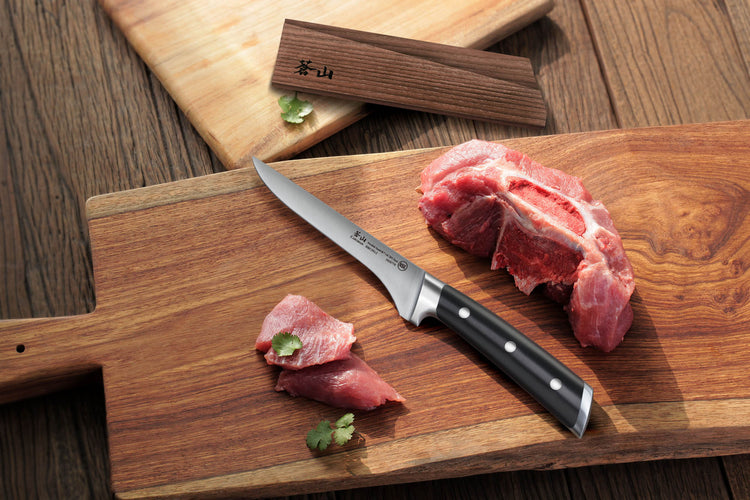 TS Series 6-inch boning knife with black handle on wooden cutting board next to raw meat and wood sheath.