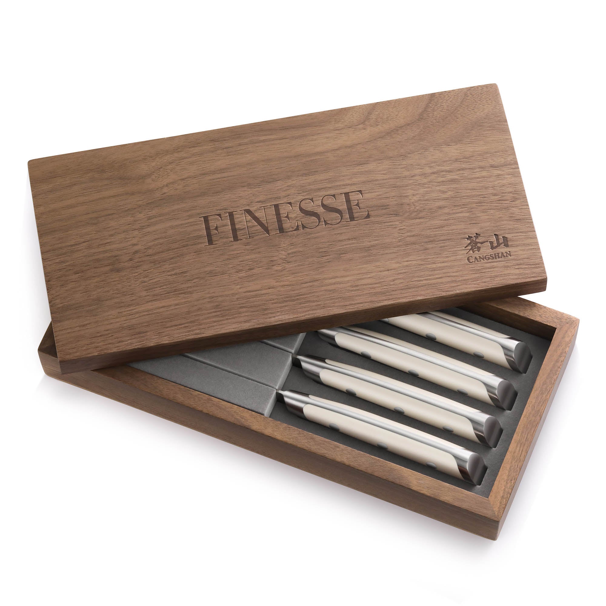 Four white-handled steak knives with straight edges in a partially open walnut box labeled 