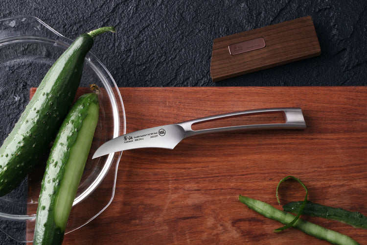 2.75-inch peeling knife with stainless steel blade and hollow handle on wooden cutting board with cucumbers and wood sheath.
