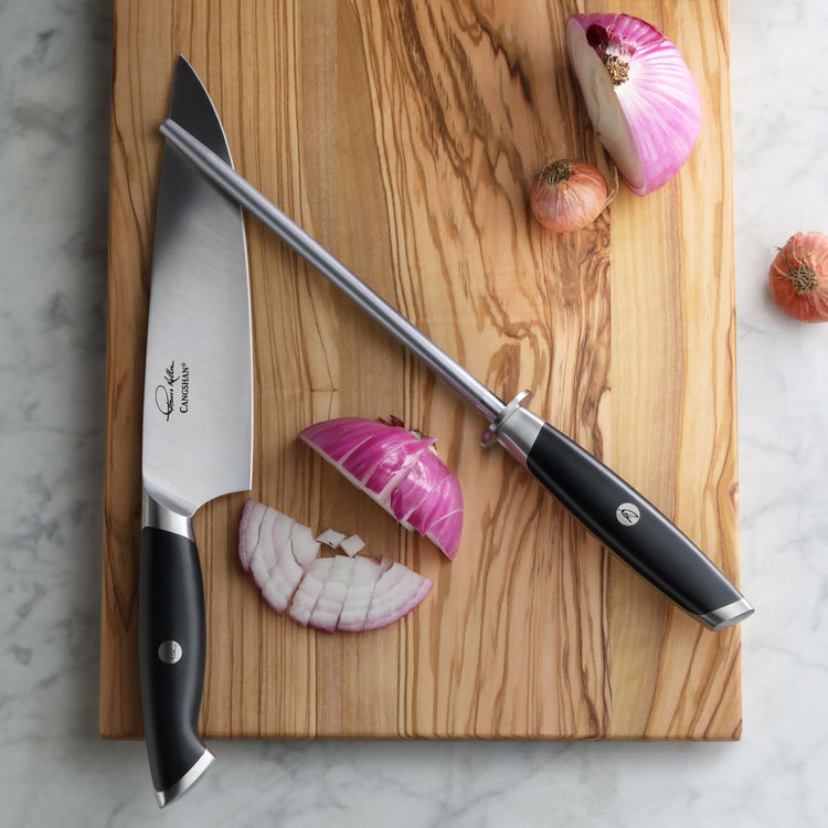 8-inch honing steel with black handle and chef's knife on wooden cutting board with sliced red onion.