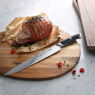 
                    
                      Carving knife with black handle on wooden board next to sliced roasted meat and scattered chili peppers and peppercorns.
                    
                  