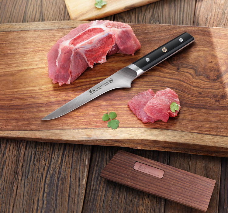 Raw pork meat with a boning knife on a wooden cutting board, garnished with small green leaves.