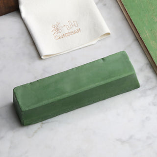 
                    
                      Green rectangular honing polish compound bar on a marble surface with a white cloth embroidered with Chinese characters nearb
                    
                  