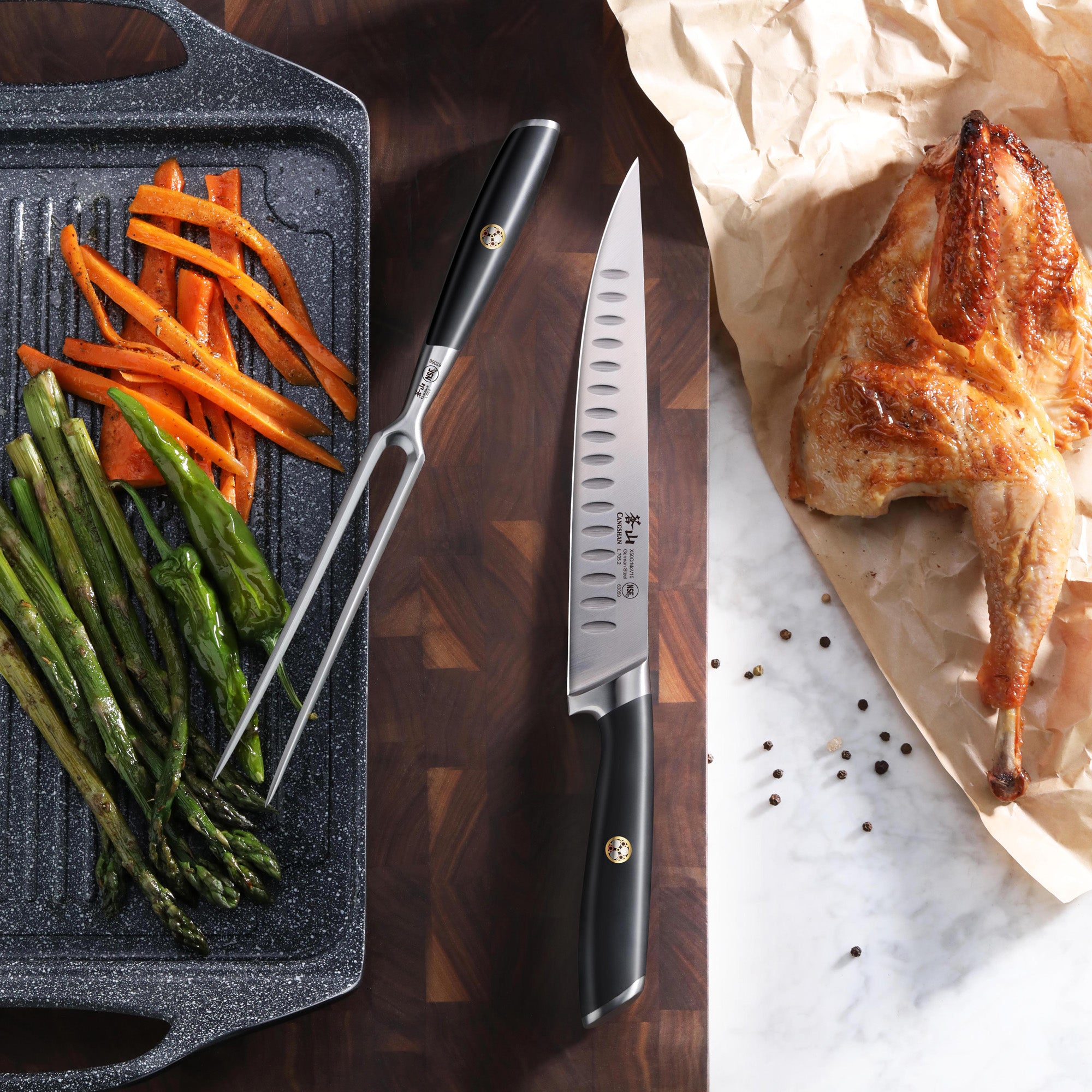 Black carving knife and fork set on a cutting board next to roasted chicken and grilled vegetables.