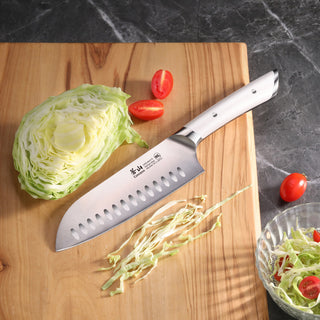 
                    
                      Santoku knife with a white handle on a wooden cutting board next to sliced cabbage and cherry tomatoes.
                    
                  