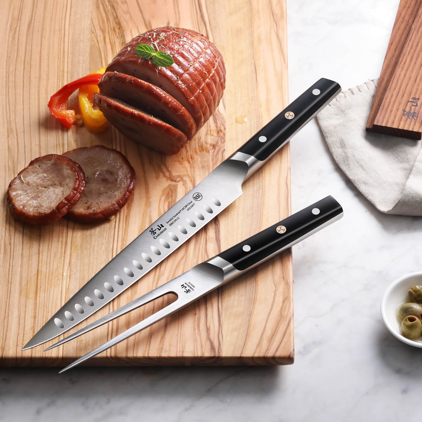 Two-piece carving set with a long serrated knife and fork on a wooden cutting board with sliced meat and vegetables.