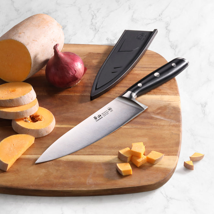 8-inch chef knife with black handle and sheath on wooden cutting board with sliced squash and red onion.