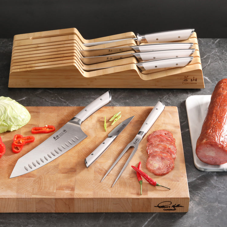 8-piece in-drawer knife set with white handles on bamboo tray, including chef knife, carving fork, and sliced meat on cutting