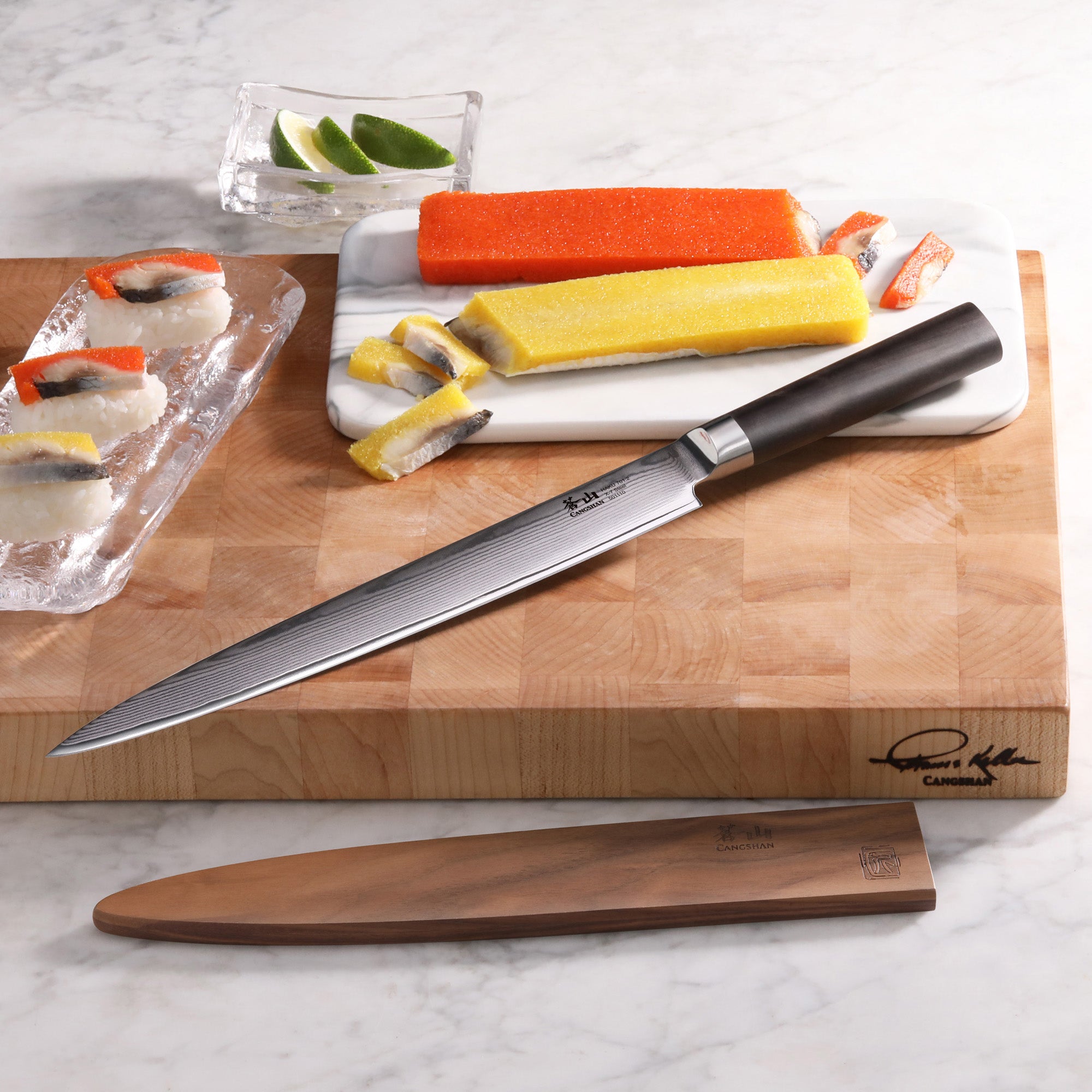 10-inch sashimi knife with black handle and wooden sheath on cutting board with sliced fish and lime wedges.