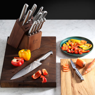 
                    
                      12-piece knife set in wooden block with sliced bell peppers and carrots on cutting boards.
                    
                  