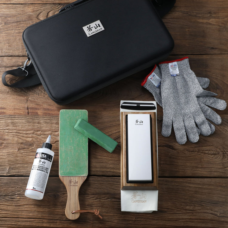 Cut resistant gloves, sharpening stone with wooden base, paddle strop with green compound, lubricant bottle, and black carryi
