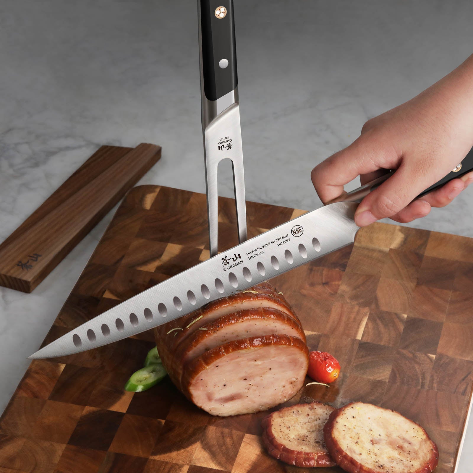Hand holding a carving knife slicing cooked meat on a wooden cutting board with a carving fork and wood sheath nearby.