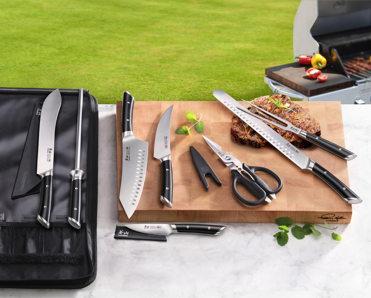 Nine-piece BBQ knife set with black handles, including knives, scissors, sharpening rod, and black carrying case on a cutting