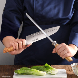 
                    
                      Person holding a knife with olivewood handle and a honing steel with wooden handle, sharpening the blade.
                    
                  