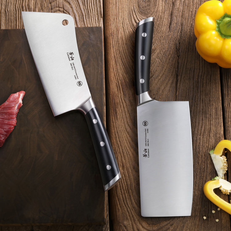 Two cleaver knives with black handles on a wooden surface, next to yellow bell peppers and a piece of raw meat.