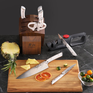 
                    
                      Knife block set with five knives and scissors in acacia wood block, two knives on cutting board with sliced citrus and pineap
                    
                  