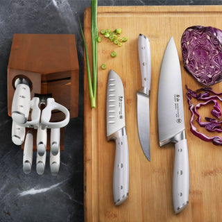 
                    
                      Set of three stainless steel knives with white handles on a wooden cutting board next to chopped green onions and purple cabb
                    
                  