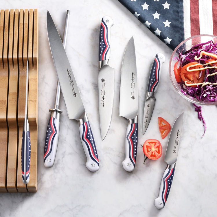 Set of five kitchen knives with American flag design handles, displayed with a wooden knife block and sliced tomato on a marb