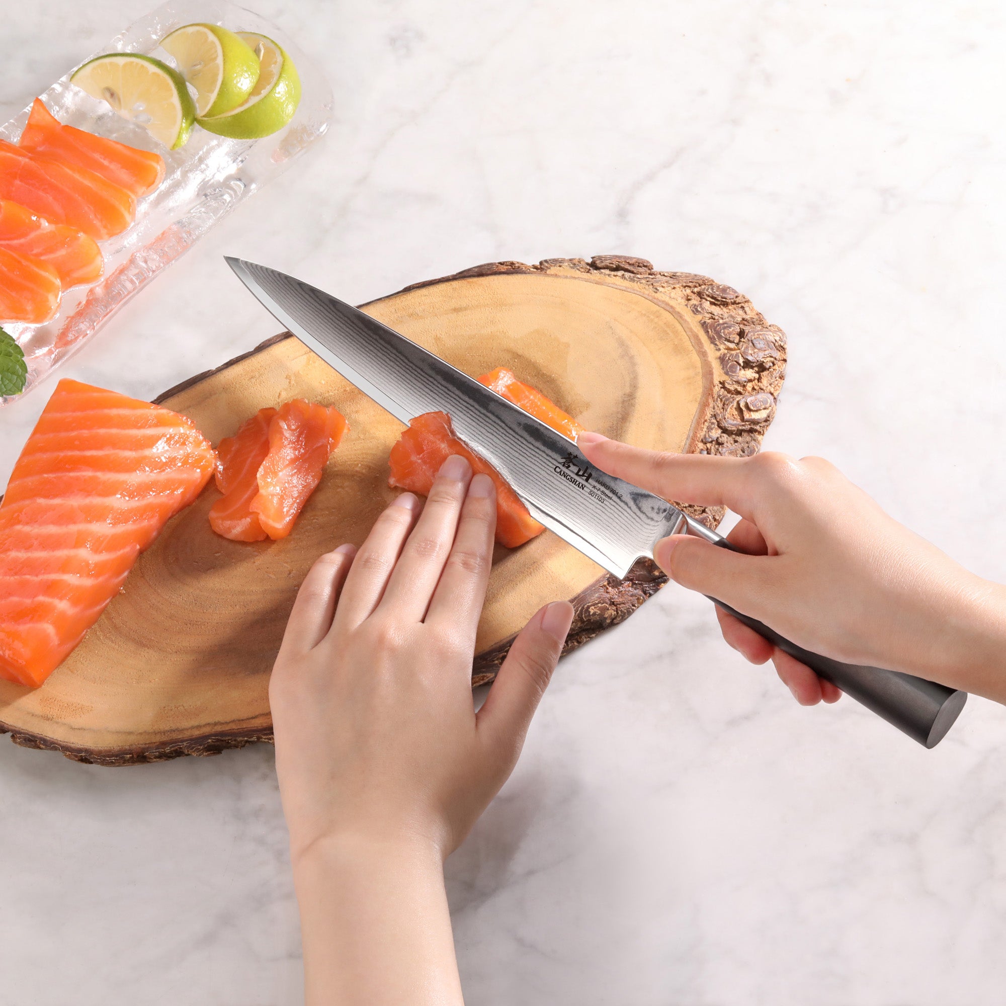 Hands slicing raw salmon on a wooden board using a sharp sashimi knife with a dark handle.