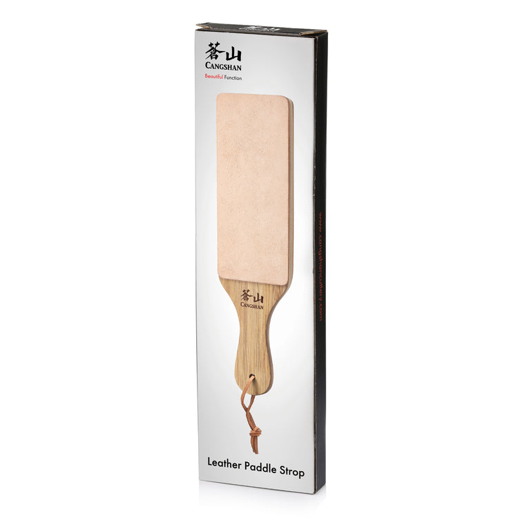 Leather paddle strop with wooden handle and hanging loop, displayed on white packaging labeled "Leather Paddle Strop.