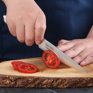 
                    
                      Hand holding a utility knife slicing a tomato on a wooden cutting board.
                    
                  