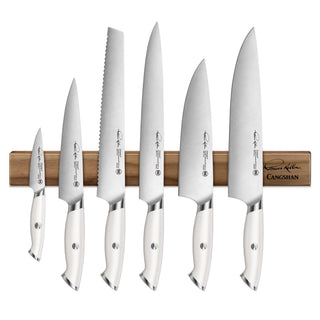 
                    
                      Seven white-handled knives with stainless steel blades displayed on a walnut magnetic knife bar.
                    
                  