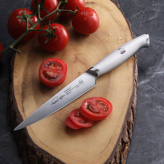 
                    
                      Utility knife with stainless steel blade and handle on wooden cutting board with sliced and whole tomatoes.
                    
                  